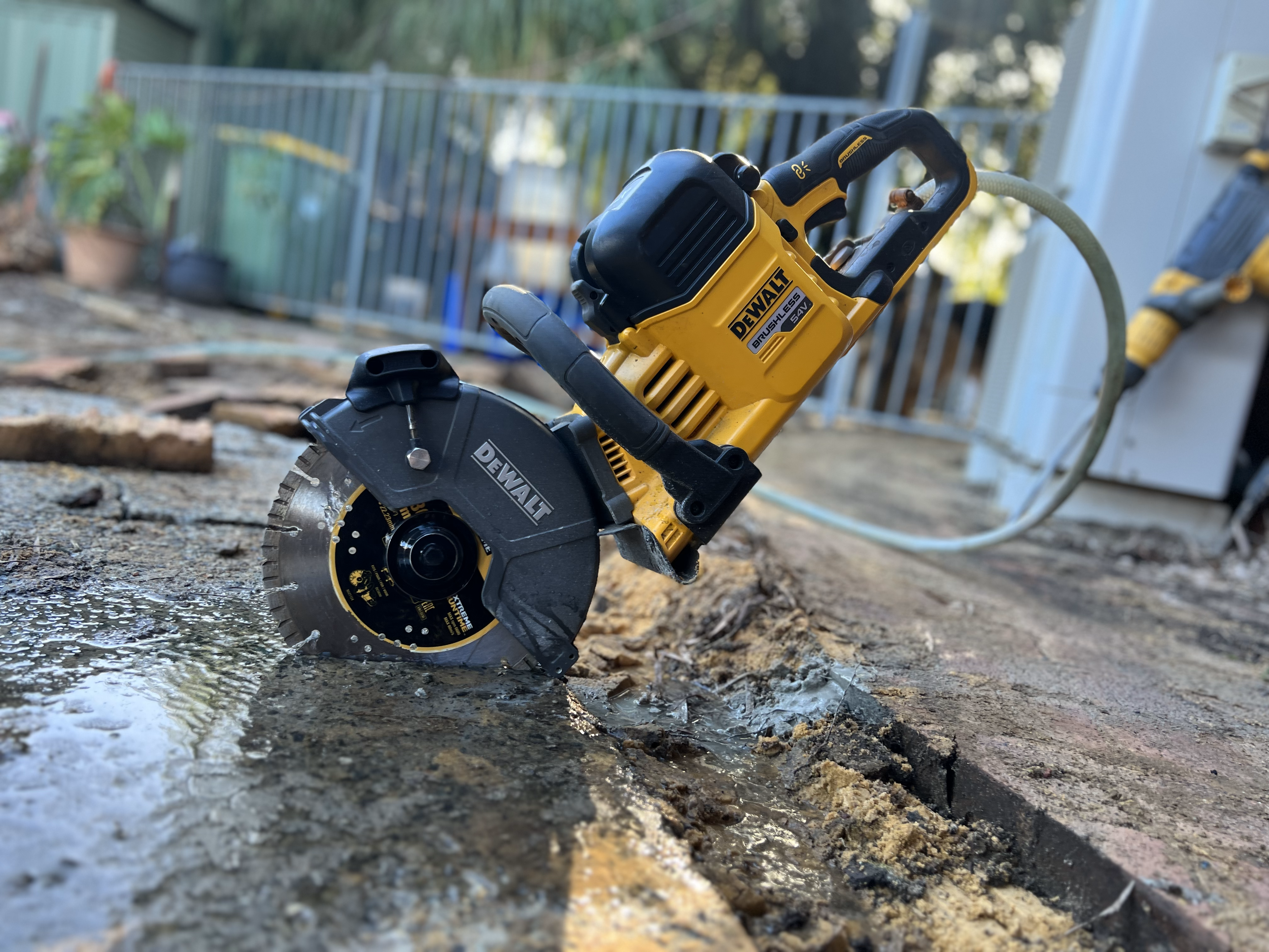 Small concrete wet saw performing demolition around a pool.